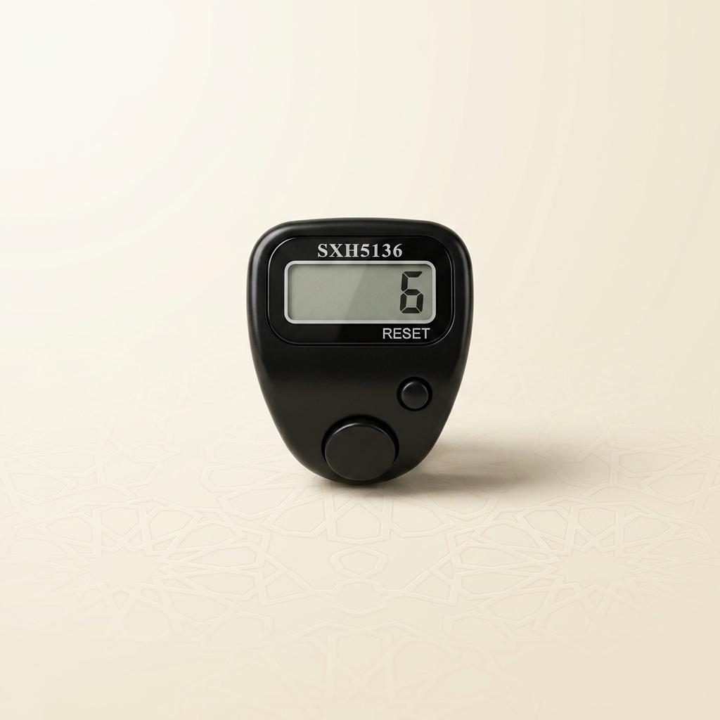 Black digital finger dhikr counter ring with an LCD display and reset button, photographed on warm ivory with a subtle Islamic geometric pattern
